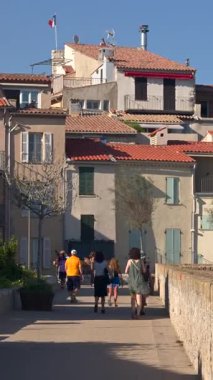 Antibes, Fransa - 20 Temmuz 2024: Kıyıdaki farklı binaların etrafında yürüyen insanları görmek. Dikey