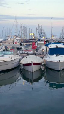 Cannes, Fransa - 15 Temmuz 2024: Bir tekne dolusu insan gün batımında Cannes Limanı 'na yanaştı. Dikey