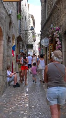 Saint Paul de Vence, Fransa - 10 Ağustos 2024: İnsanlar şehrin kaldırımlı sokaklarında yürüyor. Dikey