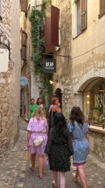 Saint Paul de Vence, Fransa - 10 Ağustos 2024: İnsanlar şehrin kaldırımlı sokaklarında yürüyor. Dikey
