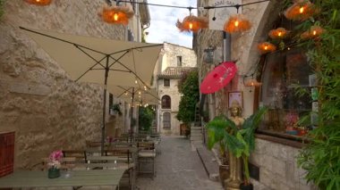 Saint Paul de Vence, Fransa - 10 Ağustos 2024: Şehrin dar, kaldırımlı bir sokağındaki teras manzarası
