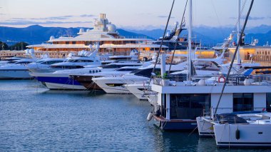 Antibes, Fransa - 13 Ağustos 2024 Akşamları Vauban Limanı 'na yanaşan tekneler ve arka planda dağlar