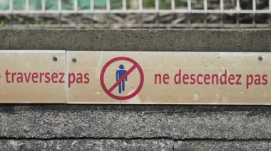 Fransızca yazılmış bir demiryolu platformunda uyarı işareti: Güvenliğiniz için: Geçmeyin, raylara gitmeyin