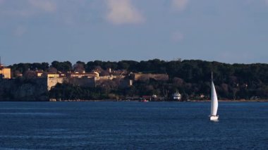 Fransa, Cannes 'da kıyıları ağaçlarla çevrili bir yelkenli.