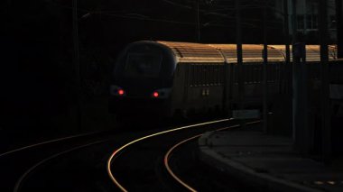 Tren gece istasyonda raylarda hareket ediyor.