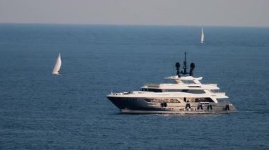 Fransız Rivierası 'nın arka planında diğer küçük teknelerle birlikte denizde hareket eden beyaz bir tekne.