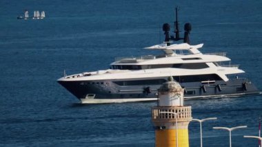Cannes, Fransa - 16 Mart 2025: Güneşli bir günde, deniz fenerinin yanında beyaz bir tekne hareket ediyor