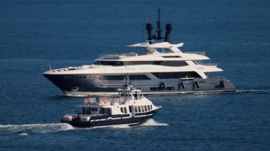 Fransız Rivierası 'nın arka planında diğer küçük teknelerle birlikte denizde hareket eden iki beyaz tekne.