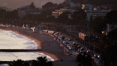 Gün batımında Fransa 'nın Cannes sahilindeki raylarda hareket eden bir trenin uzaktan görüntüsü.