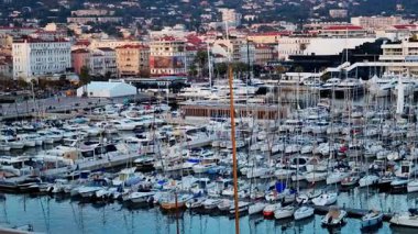 Cannes, Fransa - 15 Mart 2025: Cannes Marina 'da arka planda şehir binaları bulunan birden fazla teknenin görüntüsü
