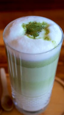 Bir kafedeki masada bir matcha latte iç. Dikey