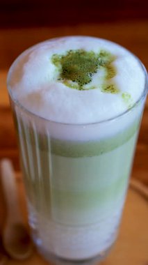 Bir kafedeki masada bir matcha latte iç. Dikey