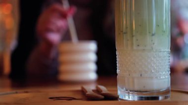 Arka planda bir kafedeki masada içki içen bir kadınla matcha latte iç.