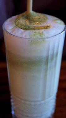 Bir kafede, bir kibrit sütlü kahveye karıştırılmış pipetin yakın çekim görüntüsü. Dikey