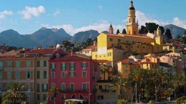 Menton, Fransa - 18 Mart 2025: Renkli binalar ve palmiye ağaçları ile çevrili Aziz Michel Bazilikası 'nın uzak manzarası