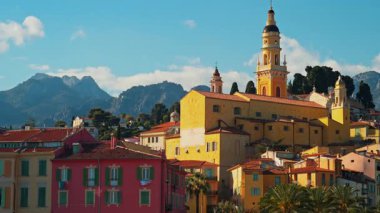 Menton, Fransa - 18 Mart 2025: Renkli binalar ve palmiye ağaçları ile çevrili Aziz Michel Bazilikası 'nın uzak manzarası