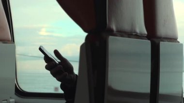 Hareket halindeki bir trenin cam koltuğunda telefonu tutan bir adam.