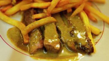 Tabağında et ve yeşil sos olan bir tabak patatesi yakın.