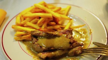 Tabağında et ve yeşil sos olan bir tabak patatesi yakın.