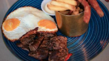 Kızarmış yumurtaları et, patates kızartması ve mavi tabağa daldırın.