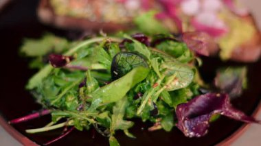 Tohumlu, turplu, kırmızı soğanlı ve siyah tabakta salatalı avokado tostunu yakın.