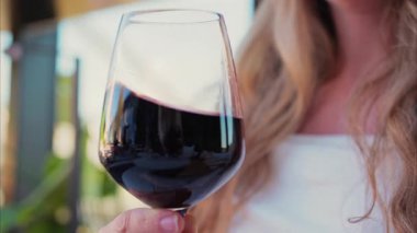 Terasta bir kadeh kırmızı şarap içen bir kadına yaklaş.