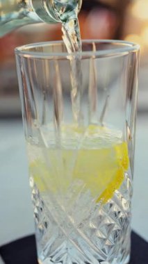 Terasta bir bardak limonun üzerine dökülen köpüklü suya yakın durun. Dikey