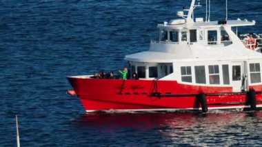 Cannes, Fransa - 16 Mart 2025: Güneşli bir günde Vieux-Port yakınlarında beyaz ve kırmızı bir tekne denizde hareket ediyor