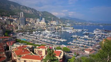 Monaco Marina 'ya kenetlenmiş teknelerin görüntüsü ve arka planda şehrin silüeti.
