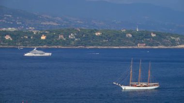 La Condamine, Monaco - 25 Ağustos 2024: Gemiler arka planda dağlarla birlikte gün ışığında denizde hareket ediyor