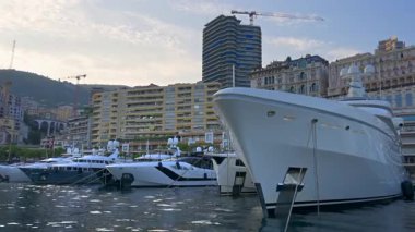 La Condamine, Monaco - 25 Ağustos 2024: Herkül Limanı 'na yanaşan ve günbatımında şehrin ufuk çizgisi olan teknelerin yakınları