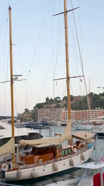 La Condamine, Monaco - 25 Ağustos 2024: Günbatımında şehrin ufuk çizgisi ile Herkül Limanı 'na yanaşan birden fazla tekneye yaklaş. Dikey