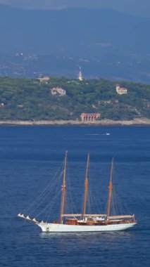 La Condamine, Monaco - 25 Ağustos 2024: Gemiler arka planda dağlarla birlikte gün ışığında denizde hareket ediyor. Dikey