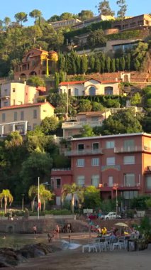 Theoule-sur-Mer, Fransa - 28 Ağustos 2024: Dağlarla çevrili Suveret plajı manzarası. Dikey