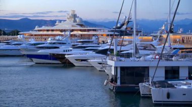Antibes, Fransa - 6 Eylül 2024 Akşamları Vauban Limanı 'na yanaşan tekneler ve arka planda dağlar
