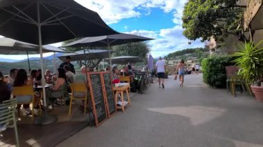 Saint Paul de Vence, Fransa - 19 Ağustos 2024: İnsanlar şehrin kaldırımlarındaki teraslarda yemek yiyor ve konuşuyor