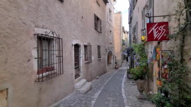Saint Paul de Vence, Fransa - 19 Ağustos 2024: Şehrin dar, kaldırımlı bir caddesinde mağazaların yakınında yürüyen insanların görüntüsü