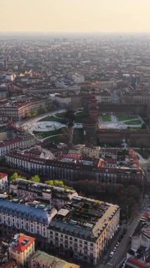 İtalya, Milan 'daki Sforzesco Kalesi' nin hava aracı görüntüsü gün batımında binalarla çevrili. Dikey