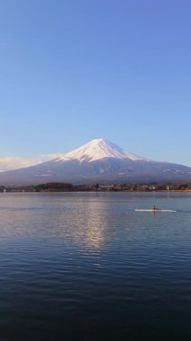 Fujikawaguchiko, Japonya - Arpil 23, 2025: Kayıkla Kawaguchiko Gölü 'nde, Fuji Dağı' nın arka planında bir adamın insansız hava aracı görüntüsü. Dikey