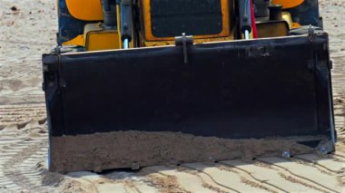 Kumsalda hareket eden sarı bir tekerlek yükleyicisinin yakınına.