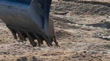 Kumsala kum saçan sarı yükleyicinin tekerleklerini kapatın.