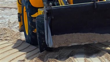 Kumsalda hareket eden sarı bir tekerlek yükleyicisinin yakınına.