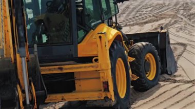 Antibes, Fransa - 2 Nisan 2025: Kumlu sahilde hareket eden sarı bir tekerlek yükleyicisine yaklaş