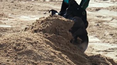 Kumsala kum saçan sarı yükleyicinin tekerleklerini kapatın.