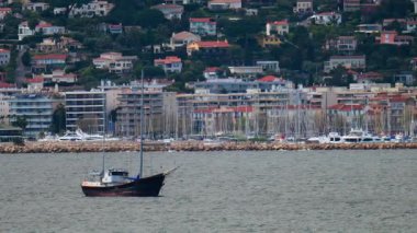 Rusty, beyaz tekne Juan-les-Pins, Fransa 'da rıhtıma yanaştı ve arka planda binalar var.