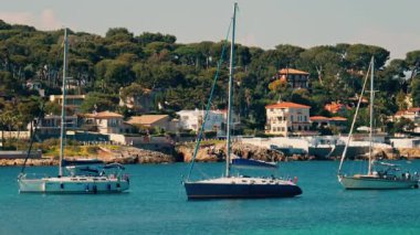 Arka planda yeşilliklerle çevrili villaları olan tekneler denize yanaştı.