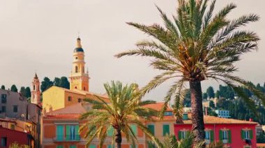 Menton, Fransa 'nın St. Michel Bazilikası manzarası renkli binalar ve palmiye ağaçları ile çevrili.