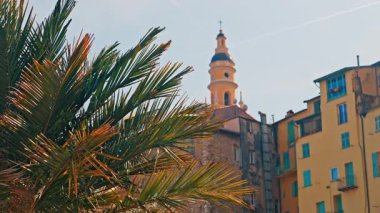 Menton, Fransa 'nın St. Michel Bazilikası manzarası renkli binalar ve palmiye ağaçları ile çevrili.