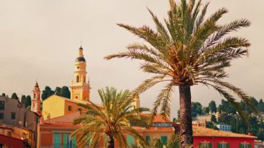 Menton, Fransa 'nın St. Michel Bazilikası manzarası renkli binalar ve palmiye ağaçları ile çevrili.