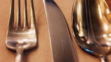 Restoranda bir çatalın, bıçağın ve kaşığın ucu peçetenin üzerinde.